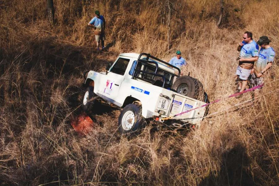 Rally Land Rover being winched up a steep slope through dry grass